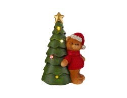 Orsetto natalizio in resina con maglione rosso accanto ad albero di Natale con stella dorata e luci LED